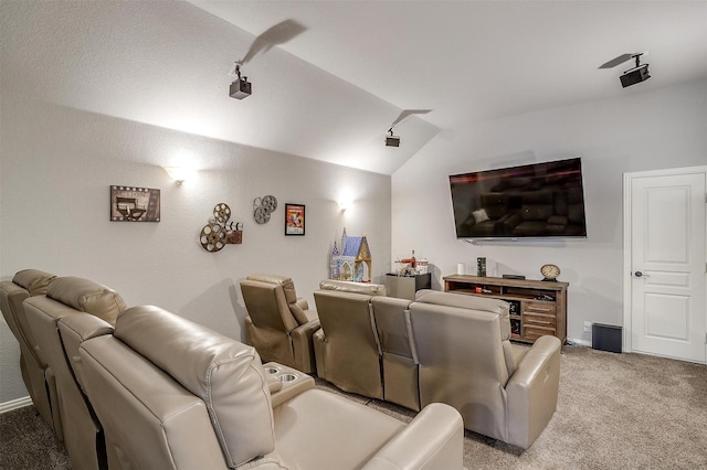 home theater room with lofted ceiling, rail lighting, light colored carpet, and baseboards