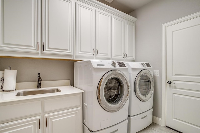 laundry area featuring light tile patterned flooring, washing machine and dryer, cabinet space, and a sink