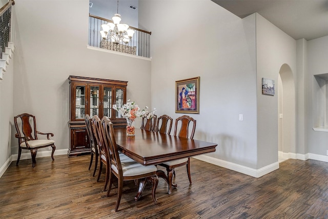 dining room with dark wood-style floors, arched walkways, and a chandelier