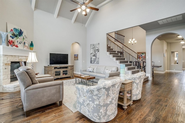 living room with visible vents, stairs, a stone fireplace, wood finished floors, and arched walkways