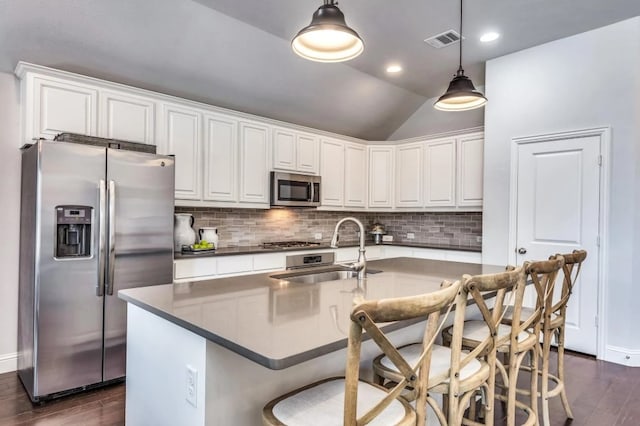 kitchen featuring visible vents, dark wood-style flooring, a sink, decorative backsplash, and appliances with stainless steel finishes