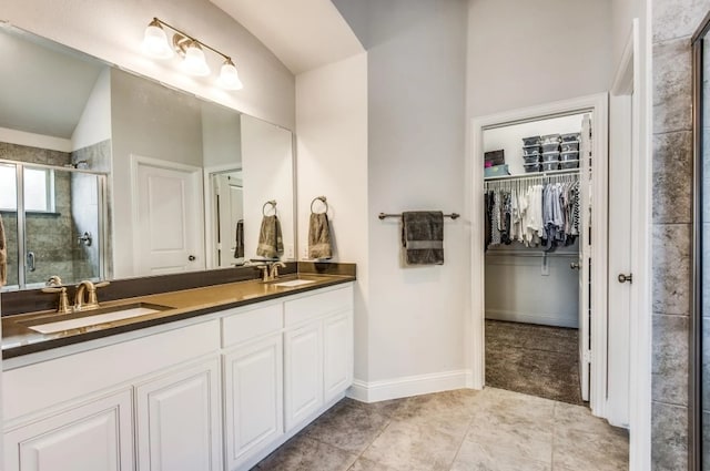 bathroom with a spacious closet, a stall shower, double vanity, and a sink