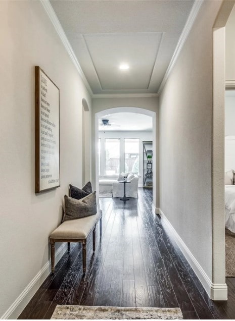 hall featuring dark wood-type flooring, crown molding, arched walkways, and baseboards