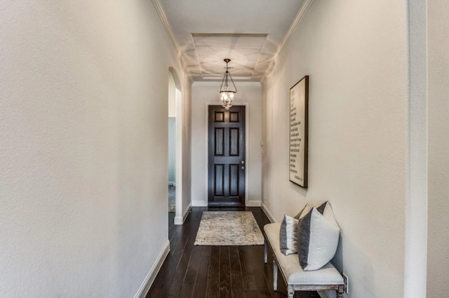 doorway to outside featuring arched walkways, dark wood-type flooring, baseboards, and ornamental molding