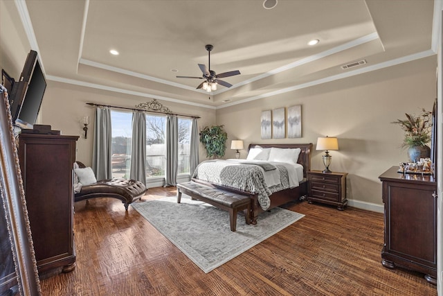 bedroom with visible vents, baseboards, a tray ceiling, and wood finished floors