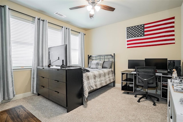 carpeted bedroom with visible vents, multiple windows, baseboards, and ceiling fan