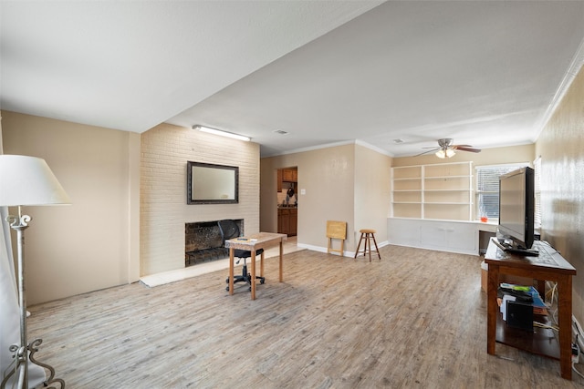 living room featuring a ceiling fan, wood finished floors, a fireplace, and ornamental molding