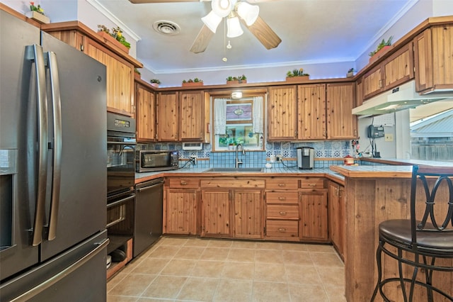 kitchen featuring brown cabinetry, a sink, stainless steel appliances, and tile counters