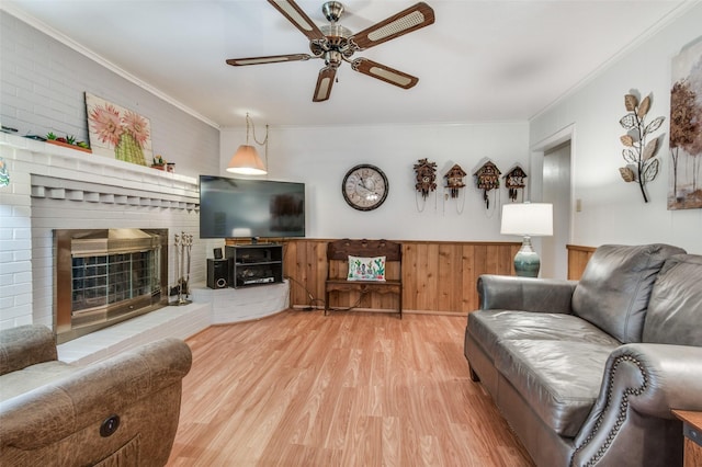 living area with a ceiling fan, light wood-style floors, a fireplace, and crown molding