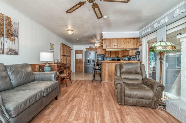 living room featuring crown molding, light wood-type flooring, and a ceiling fan