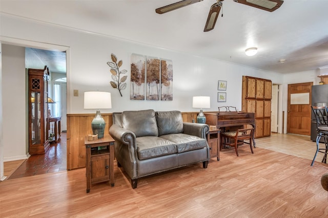 living area with crown molding, light wood-type flooring, and a ceiling fan