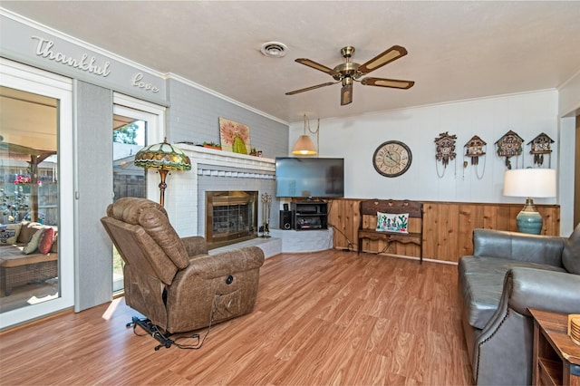 living room featuring visible vents, wood finished floors, a fireplace, and crown molding