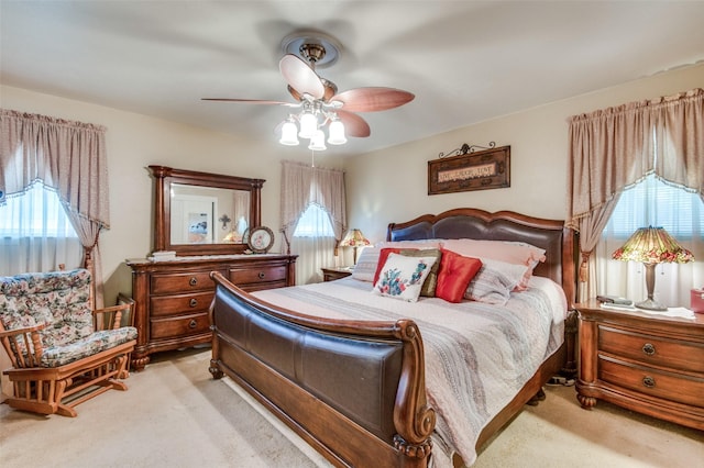 bedroom with light colored carpet, a ceiling fan, and multiple windows