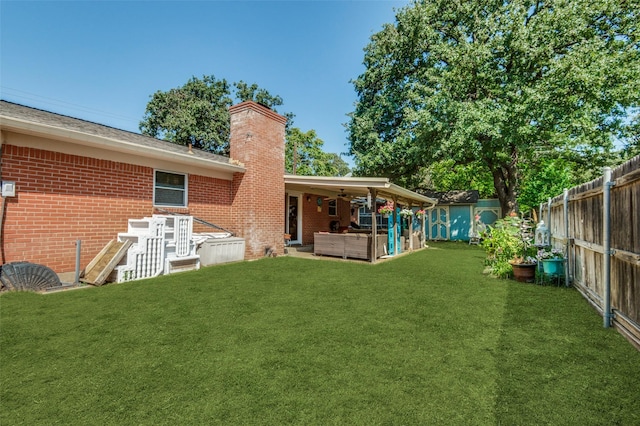 view of yard with an outbuilding, a patio, a fenced backyard, ceiling fan, and outdoor lounge area