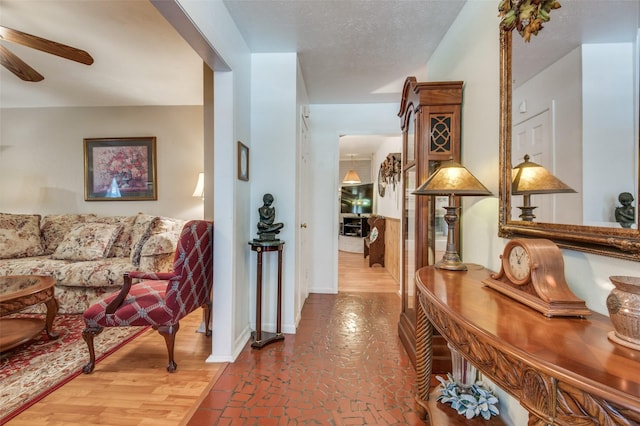 hallway with baseboards, brick floor, and a textured ceiling