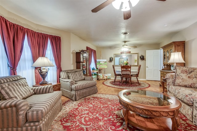 living room featuring light wood finished floors, baseboards, and ceiling fan