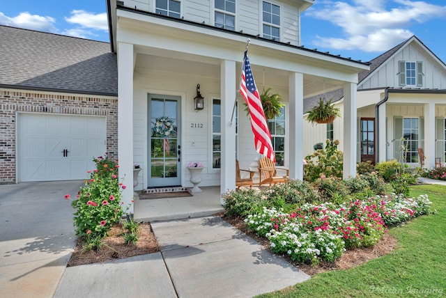 view of exterior entry with board and batten siding, a porch, brick siding, and a garage