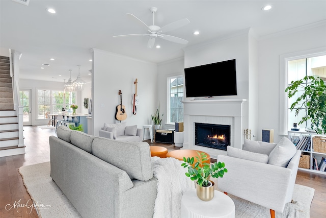 living room with stairway, wood finished floors, a fireplace with flush hearth, recessed lighting, and ornamental molding