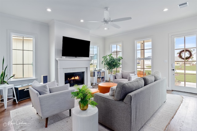 living area featuring visible vents, a fireplace, crown molding, and wood finished floors