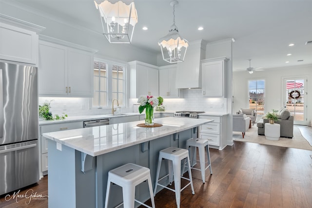 kitchen featuring dark wood finished floors, a sink, white cabinets, appliances with stainless steel finishes, and a center island