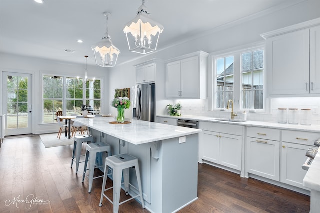 kitchen with light stone counters, decorative backsplash, an inviting chandelier, stainless steel appliances, and a sink