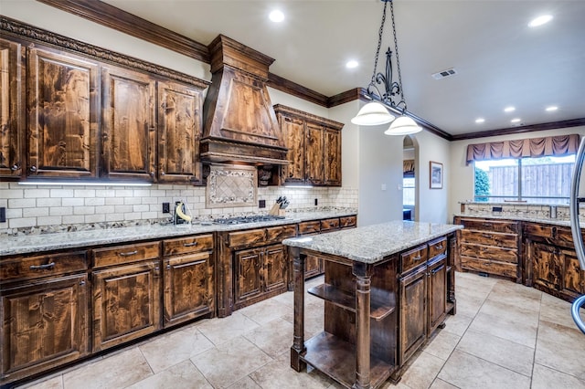 kitchen featuring tasteful backsplash, custom range hood, ornamental molding, light stone counters, and arched walkways