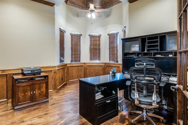 office space with a high ceiling, wood finished floors, a wainscoted wall, and ceiling fan