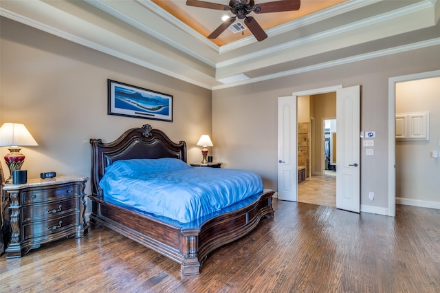 bedroom with a tray ceiling, wood finished floors, visible vents, and ornamental molding