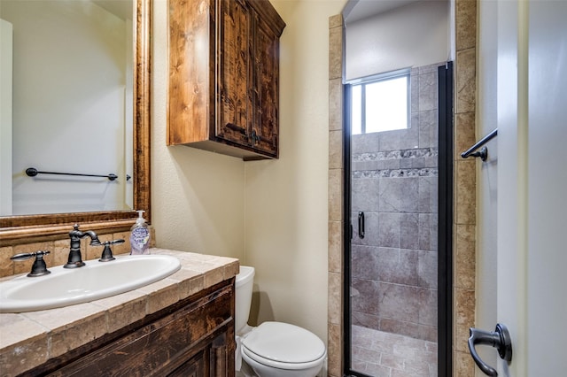 bathroom featuring toilet, a stall shower, and vanity