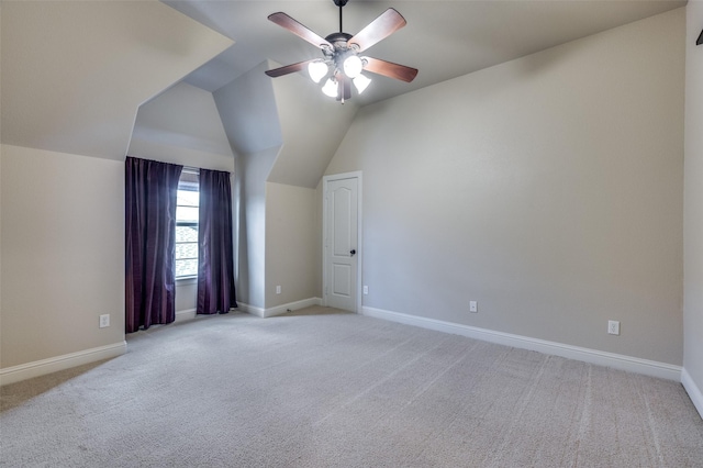 additional living space with baseboards, light carpet, and vaulted ceiling