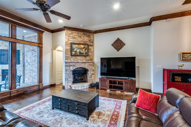 living room featuring crown molding, baseboards, a fireplace, wood finished floors, and a ceiling fan