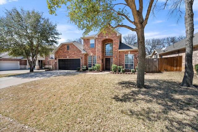 traditional-style home featuring brick siding, a front lawn, fence, concrete driveway, and an attached garage