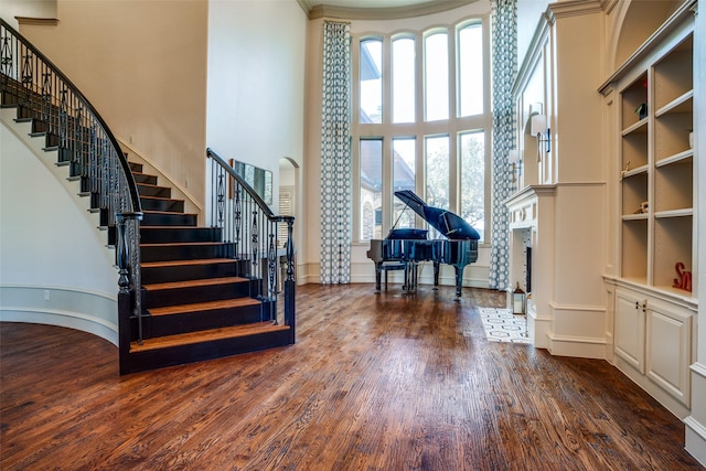 interior space featuring a towering ceiling, stairs, dark wood finished floors, and a fireplace