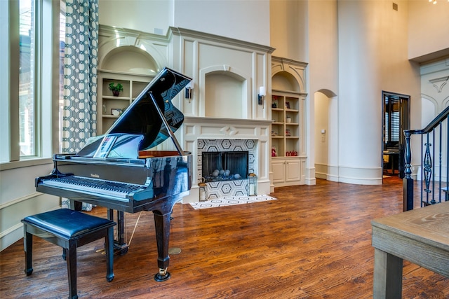 interior space featuring a towering ceiling, stairs, dark wood finished floors, and a fireplace