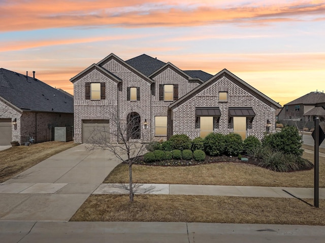 french country inspired facade with brick siding, concrete driveway, and an attached garage