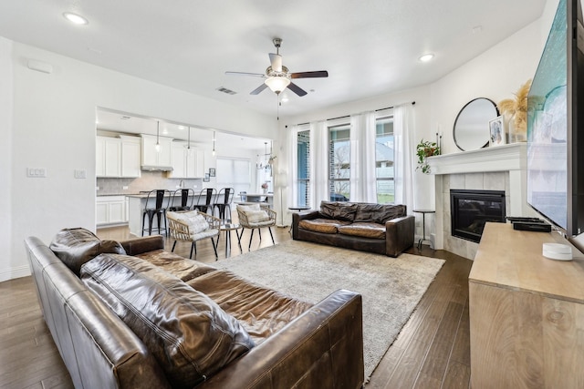 living area featuring hardwood / wood-style floors, a ceiling fan, visible vents, recessed lighting, and a fireplace