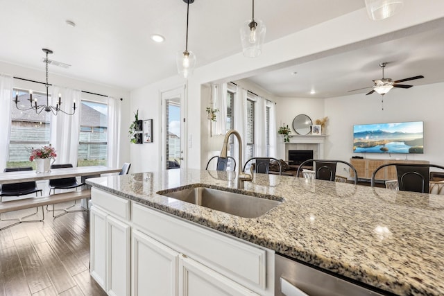 kitchen featuring a sink, decorative light fixtures, wood finished floors, white cabinetry, and a tile fireplace