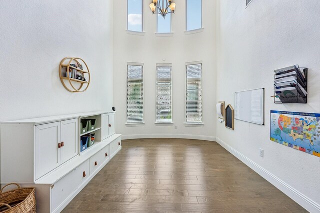 living area featuring a healthy amount of sunlight, dark wood-style floors, baseboards, and a chandelier
