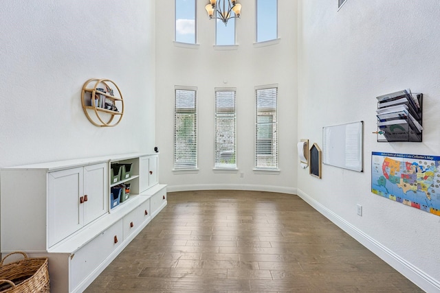 living room featuring an inviting chandelier, dark wood-style floors, baseboards, and a healthy amount of sunlight