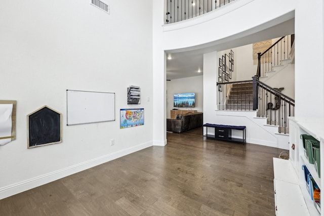 unfurnished living room with stairway, wood finished floors, visible vents, and baseboards