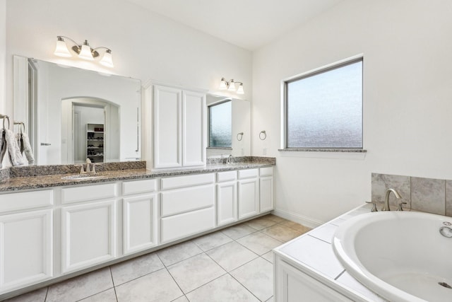 bathroom featuring double vanity, a sink, a spacious closet, tile patterned floors, and a bath