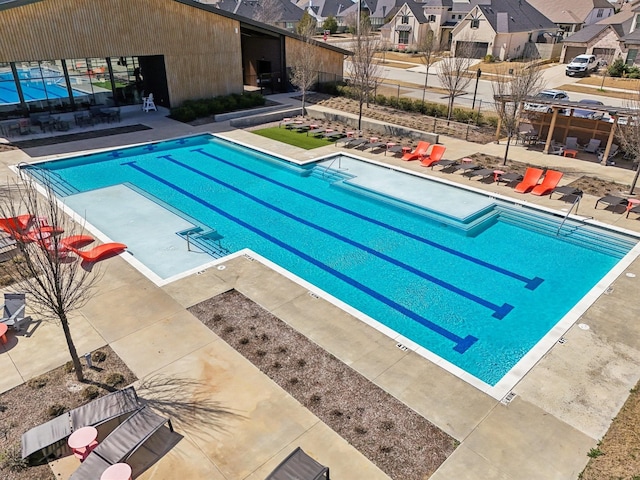 community pool featuring a patio, fence, and a residential view