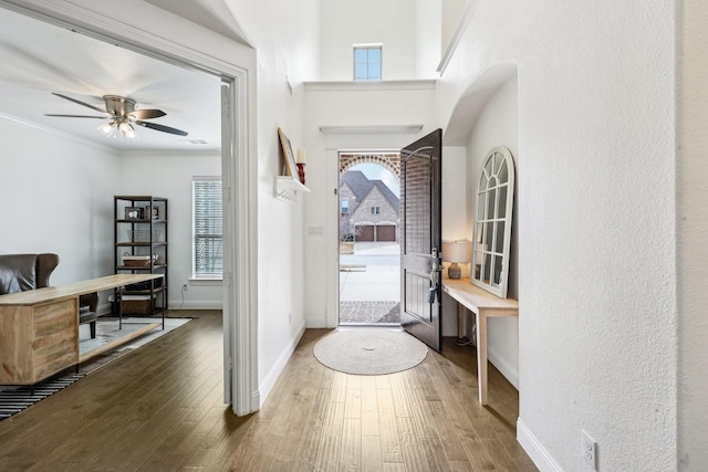 entrance foyer featuring baseboards, wood finished floors, a ceiling fan, and crown molding