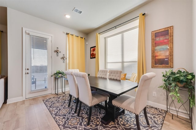 dining area featuring light wood finished floors, visible vents, and baseboards