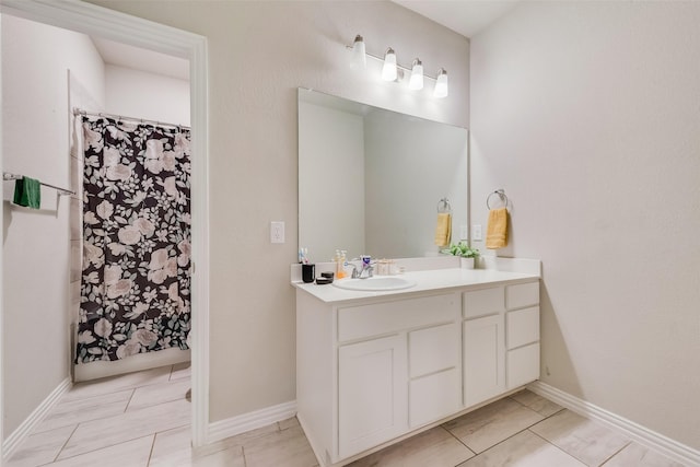 bathroom with vanity, a shower with shower curtain, and baseboards