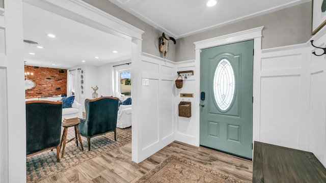 foyer featuring recessed lighting, a decorative wall, light wood-style flooring, and visible vents