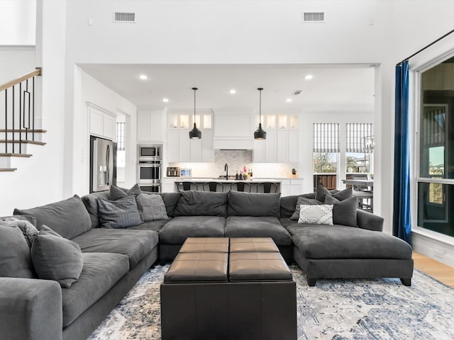 living area featuring recessed lighting, visible vents, light wood-style floors, and stairway