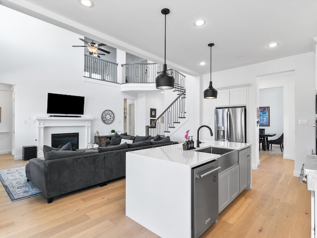 kitchen featuring pendant lighting, a fireplace, light wood-style floors, stainless steel appliances, and a sink