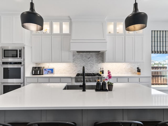 kitchen with tasteful backsplash, a breakfast bar area, light countertops, appliances with stainless steel finishes, and custom exhaust hood