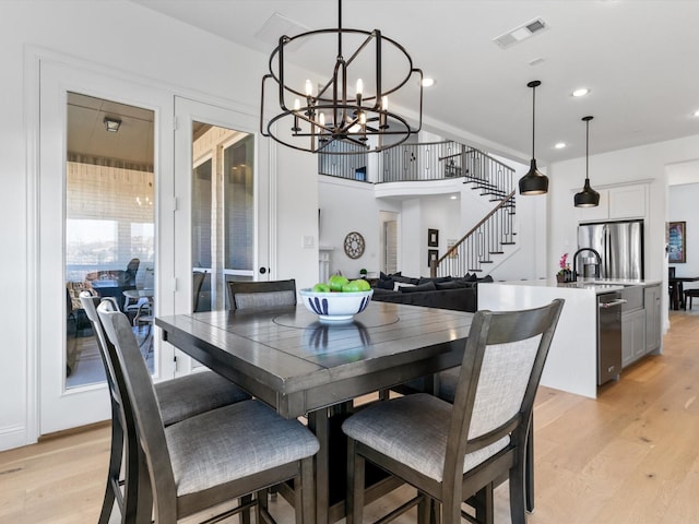 dining space with visible vents, light wood finished floors, recessed lighting, stairs, and a notable chandelier